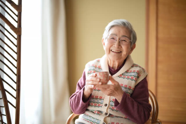 笑顔でカップを持つ高齢女性