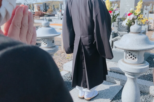 墓地を歩く僧侶と祈る人々